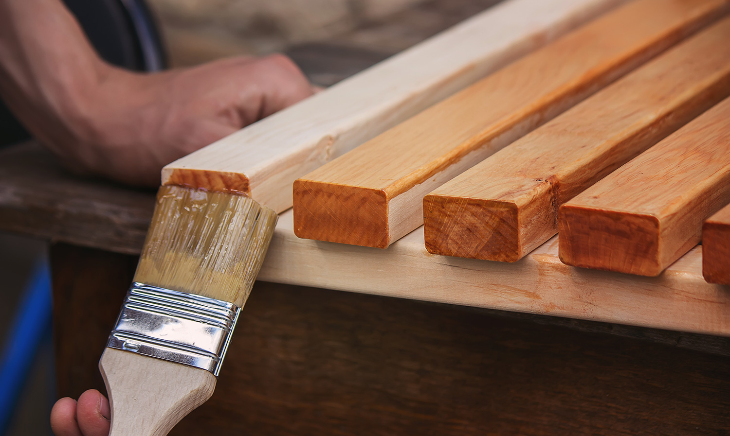 Pintando madera con pincel en taller de carpintería.